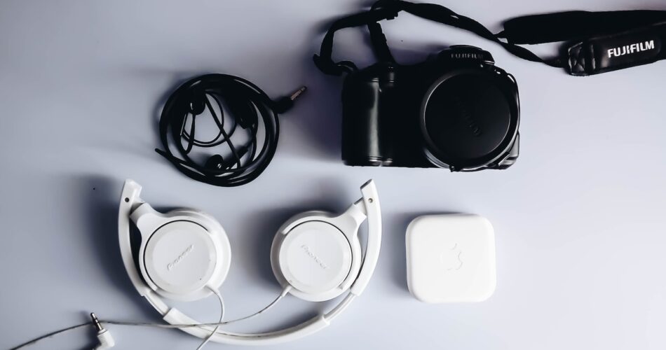 black Fujifilm DSLR camera and white corded headphones